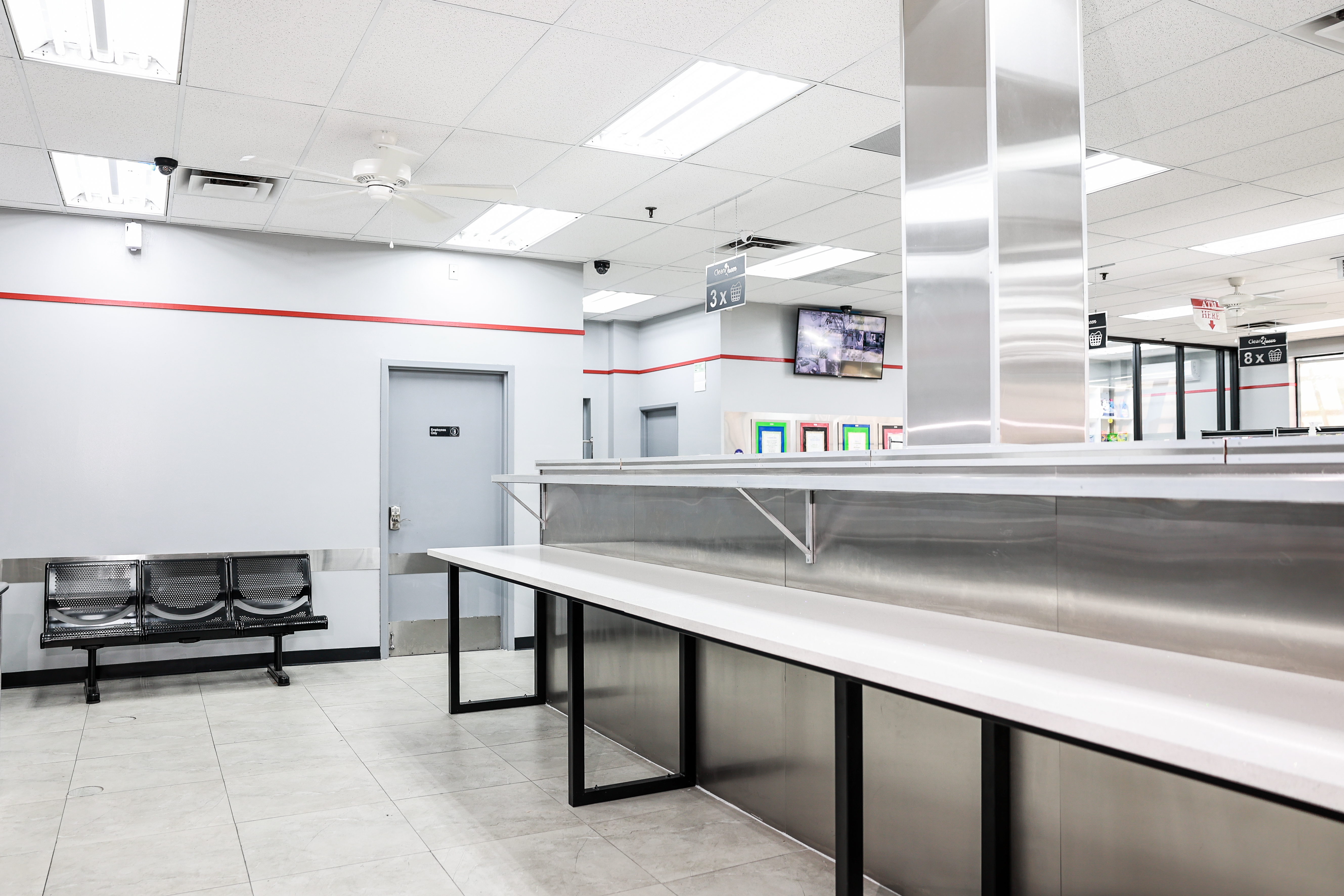 Folding stations beside large-capacity dryers at Clean Queen Laundry